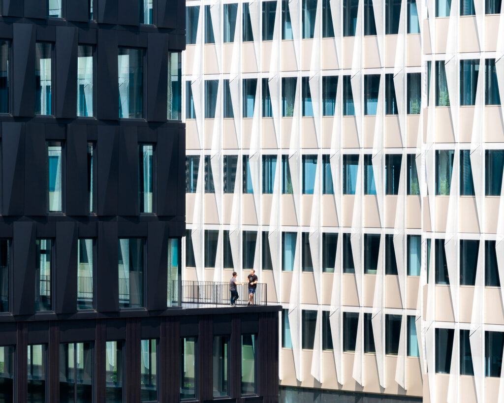 Photo by Brad Feinknopf ’86 showing two people on a terrace surrounded by the architectural patterns of the Digital Futures office complex in Cincinnati, OH