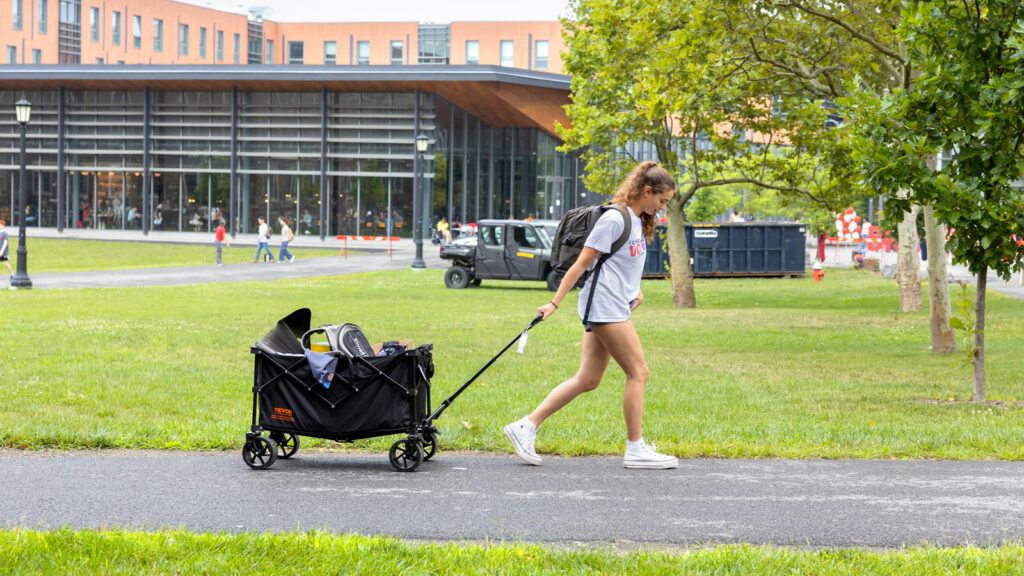 A new student pulls a cart full of belongings on North Campus