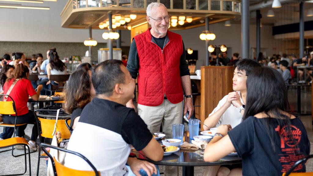 President Mike Kotlikoff speaks two a family sitting at a table in Morrison Dining