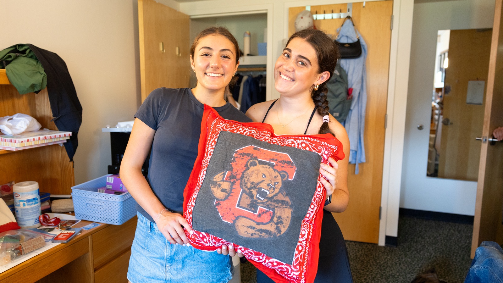 Two students hold a Cornell-branded pillow while moving into their residence hall room during Move-In, August 2026
