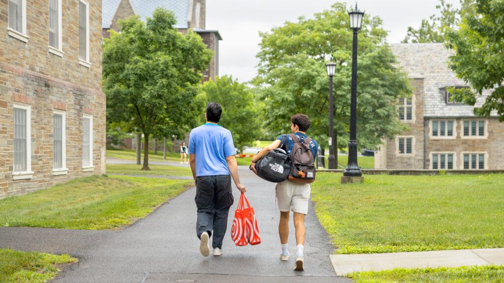 Two new students carry belongings on campus