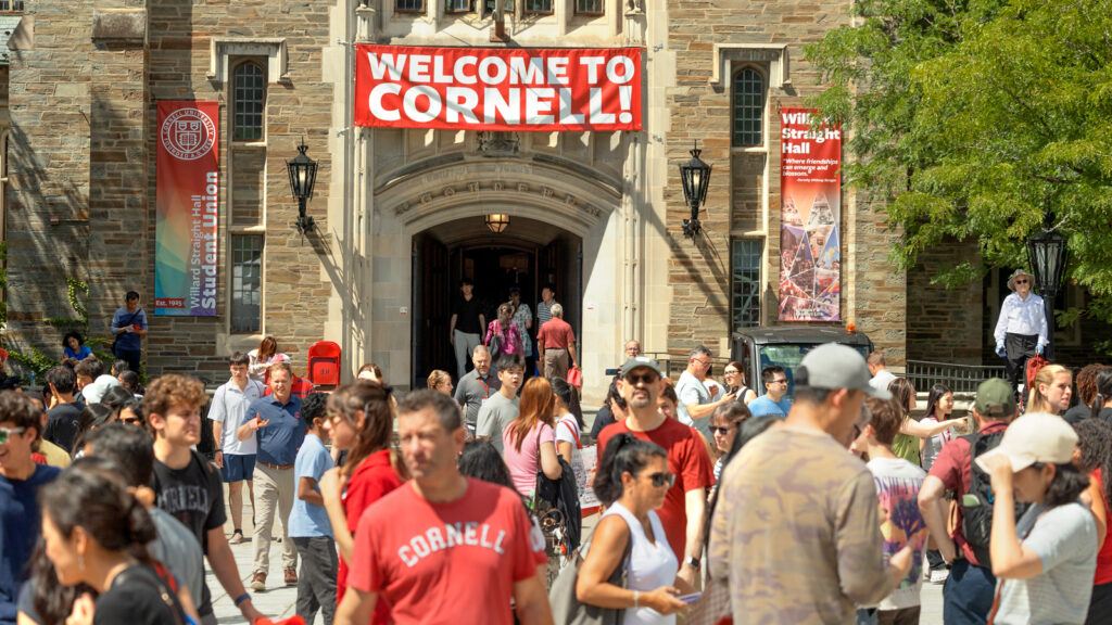 A crowd outside Willard Straight, which has a WELCOME TO CORNELL! sign