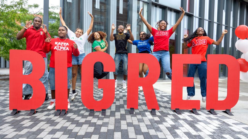 students jump and cheer on North Campus behind letters spelling out "BIG RED" during Move-In events, August 2026