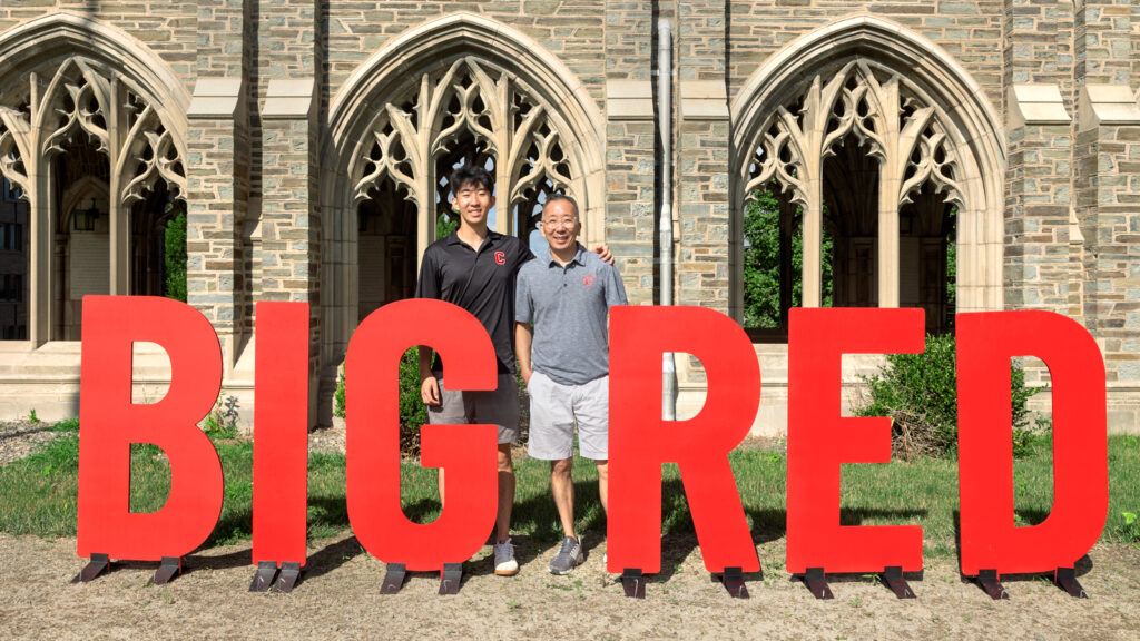 a student and parent pose for a photo on West Campus by letters spelling out "BIG RED"