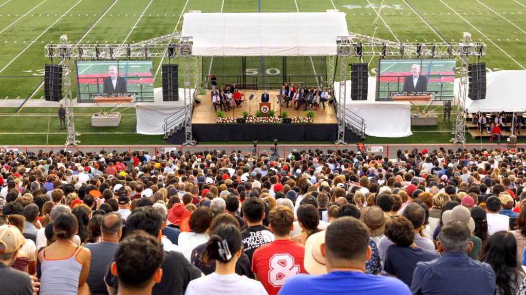 President Michael Kotlikoff, visible on the stage and on two large adjacent screens, addresses the crowd during New Student Convocation Aug. 18, 2026 at Schoellkopf Field