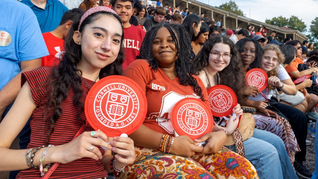Students and parents display circular Cornell insignia-shaped fans during New Student Convocation Aug. 18, 2026 at Schoellkopf Field