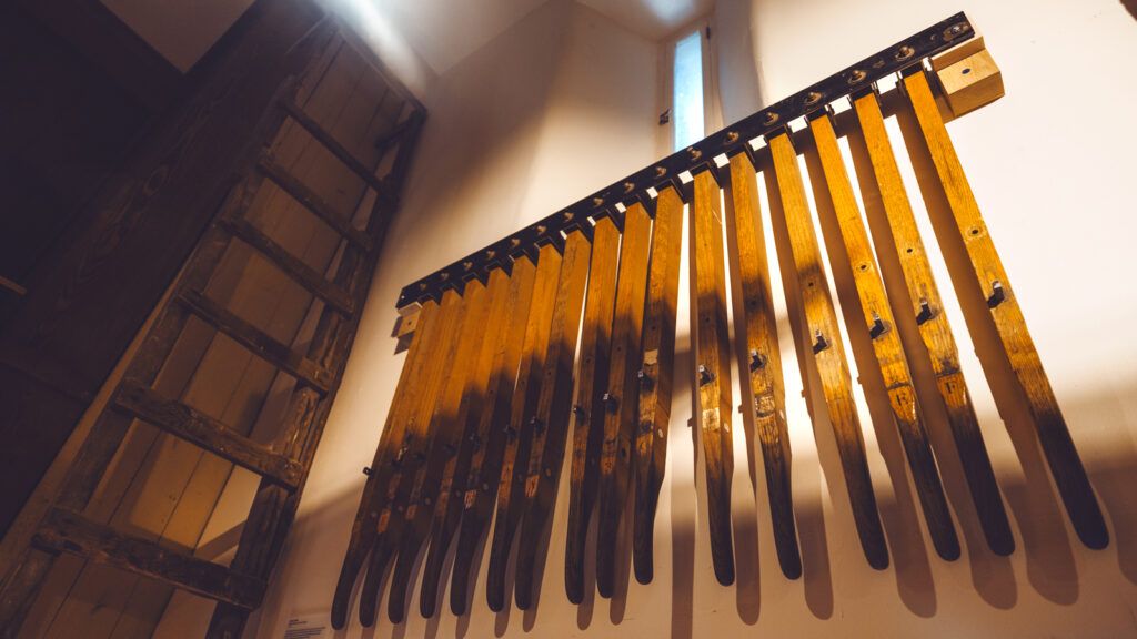 a worn set of wooden playing levers, once part of the Cornell Chimes playing stand, and a ladder once used to reach books on the shelves in the tower, are displayed in one corner of the Chimes Museum