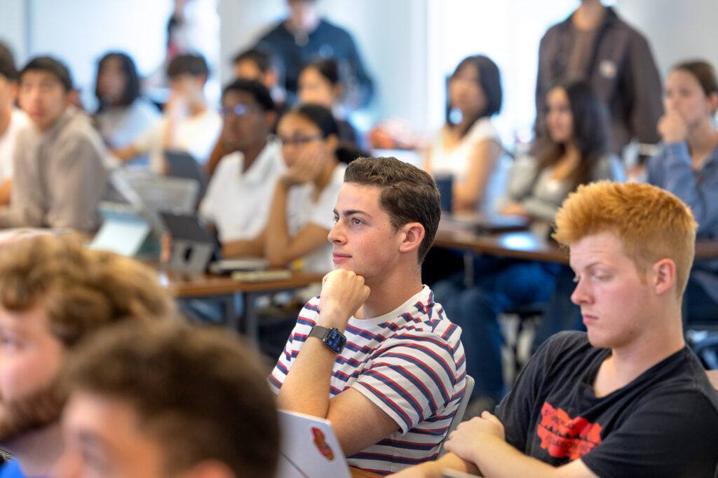 Students sit in class and listen attentively with laptops in front of them