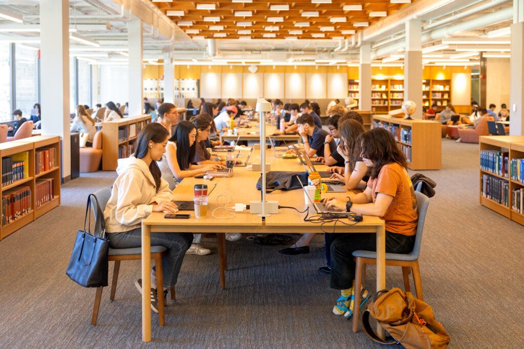 Students sit at either side of large tables in Olin Library on their laptops