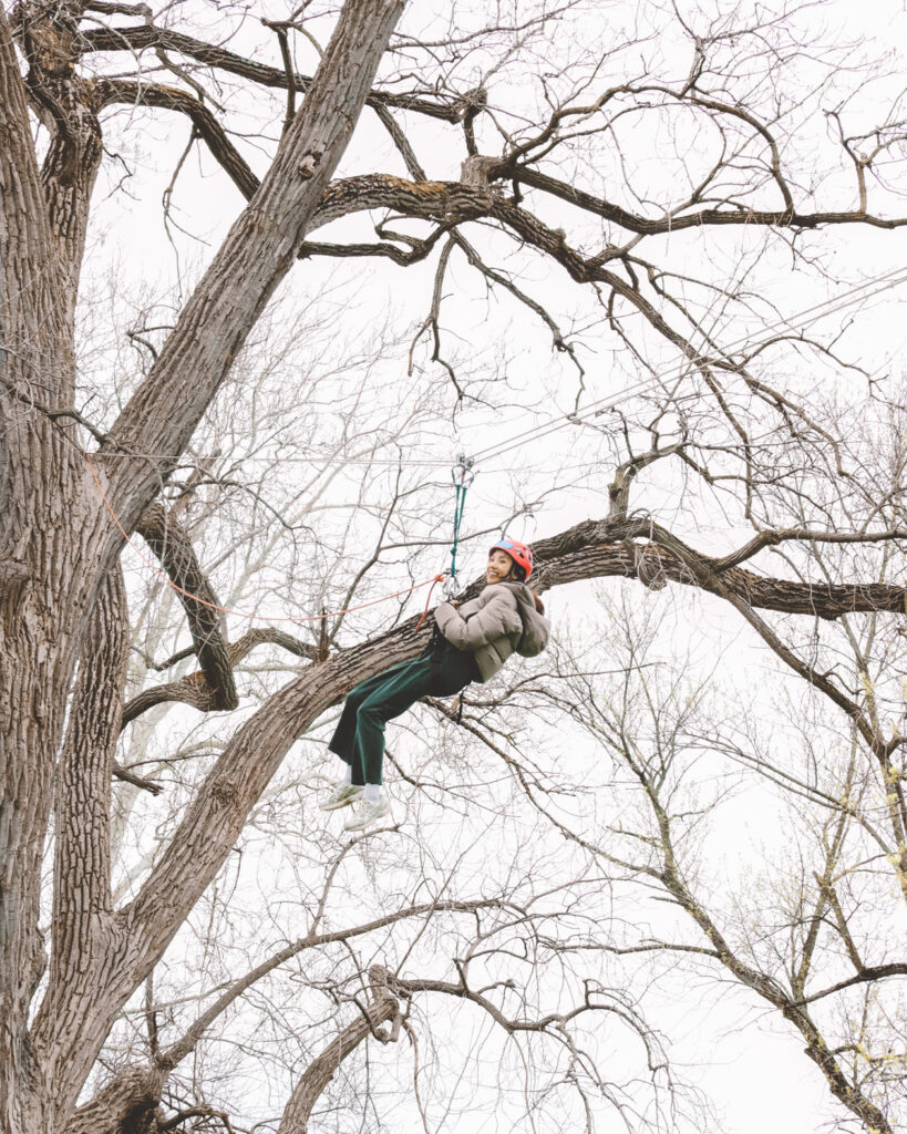 A student zip lines from a tree during a PE class at Stewart Park.