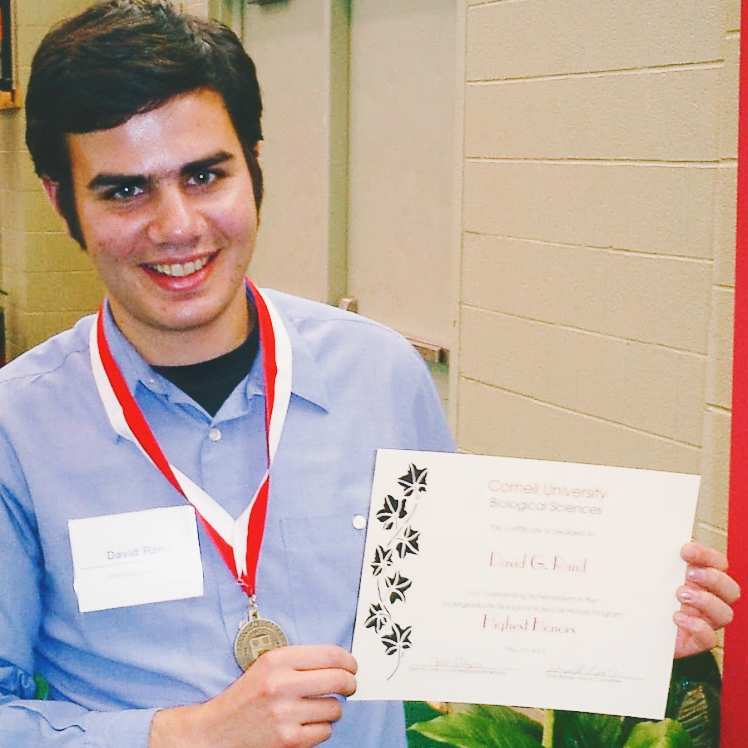 David Rand as a Cornell student holds up a certificate