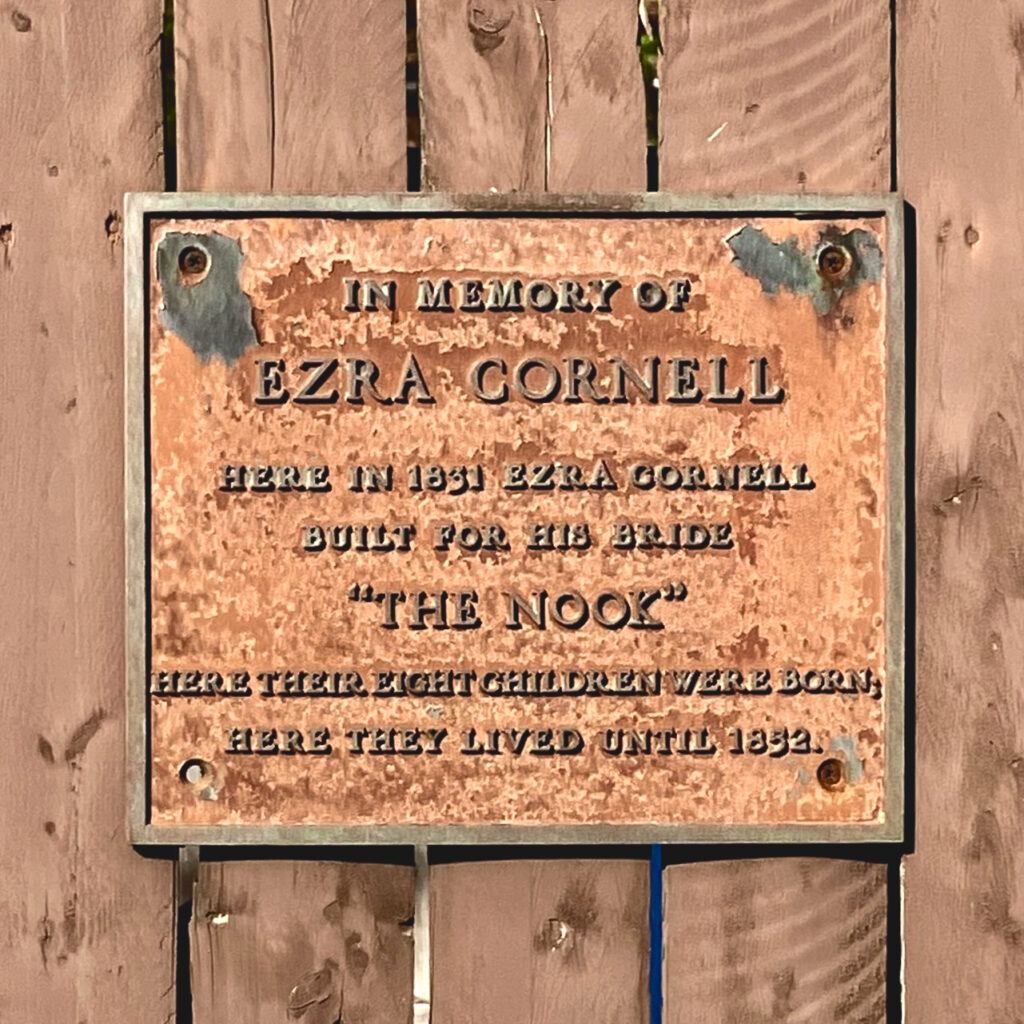 A weathered plaque that says "In memory of Ezra Cornell -- Here in 1831 Ezra Cornell built for his bride 'The Nook' -- Here their eight children were born -- Here they lived until 1852"