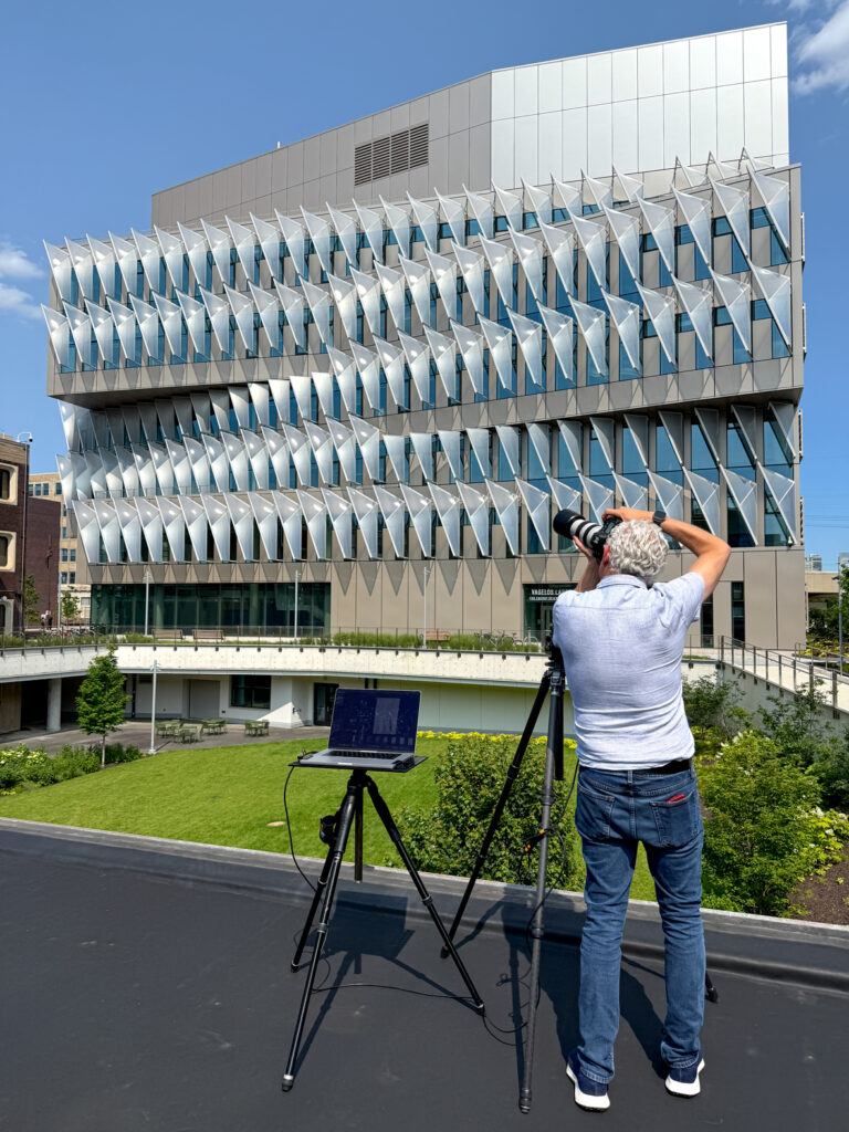 Image of Brad Feinknopf at work photographing a building, with camera, tripods and laptop