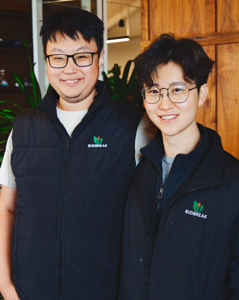 Ertai Liu and Jonathan Moon stand next to each other smiling, both wearing black coats with the Budbreak logo.