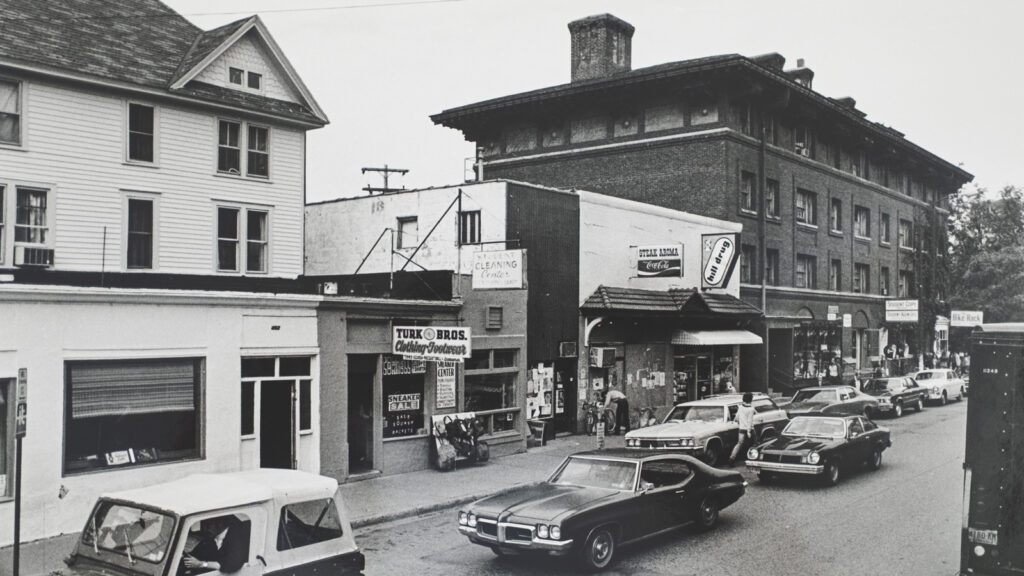 view of College Avenue looking north in the early 1970s, showing several retail shops and Sheldon Court to the right