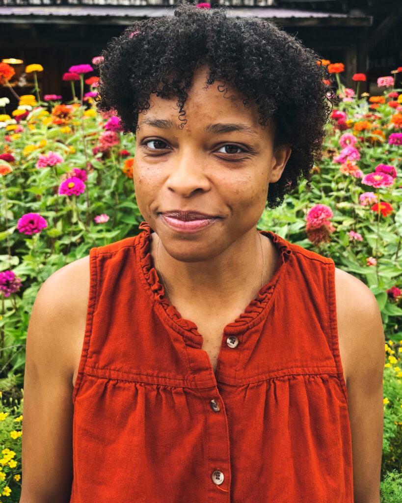 Finley Williams wearing a red sleeveless blouse in front of flowers