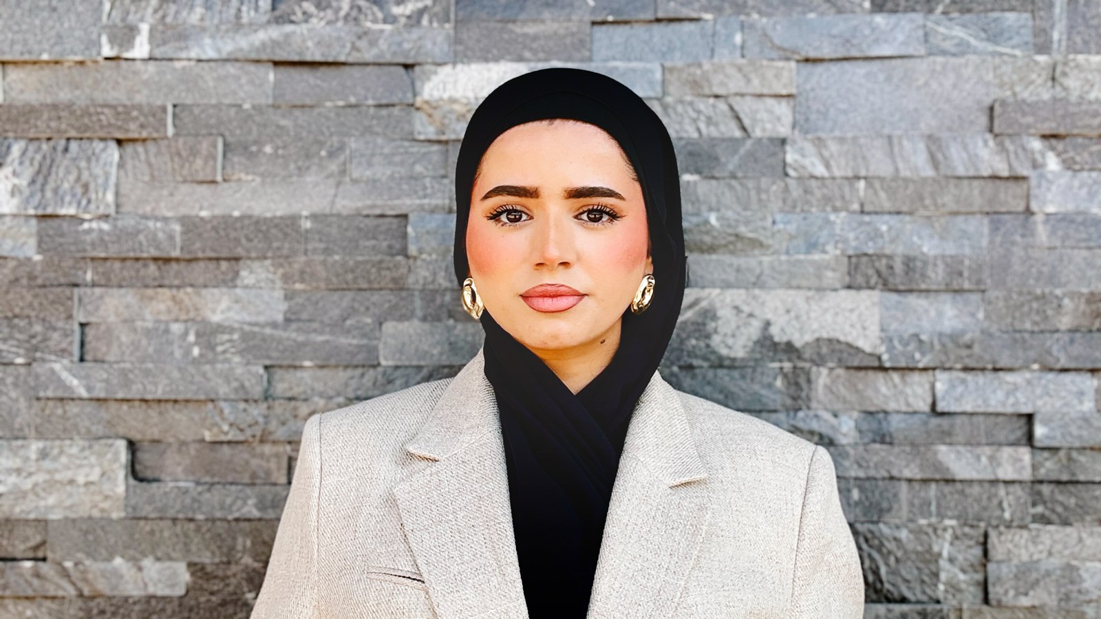Mursal Rahim wearing a tan blazer and gold hoop earrings.