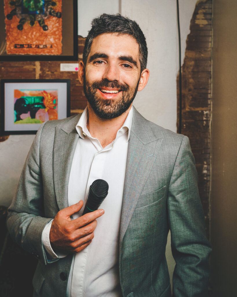 Daniel Anastasio smiles with a small microphone in his hand.