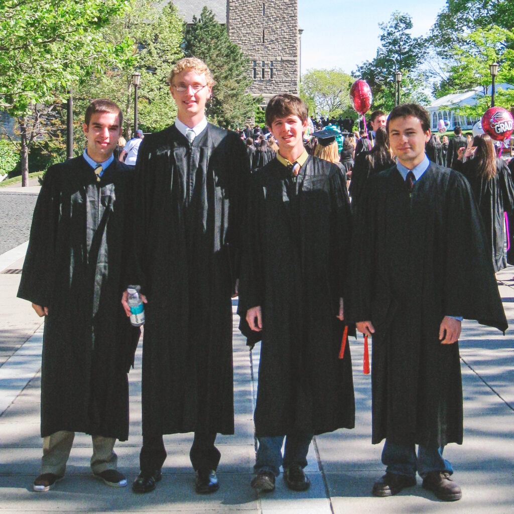 Patrik Nichols with three classmates at Commencement, wearing caps and gowns