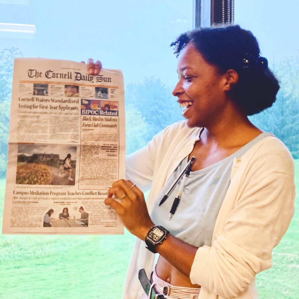 Finley Williams holding up a copy of the Cornell Daily Sun