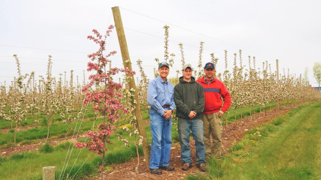 Bobby Brown stands in between his father and uncle in the apple orchard.