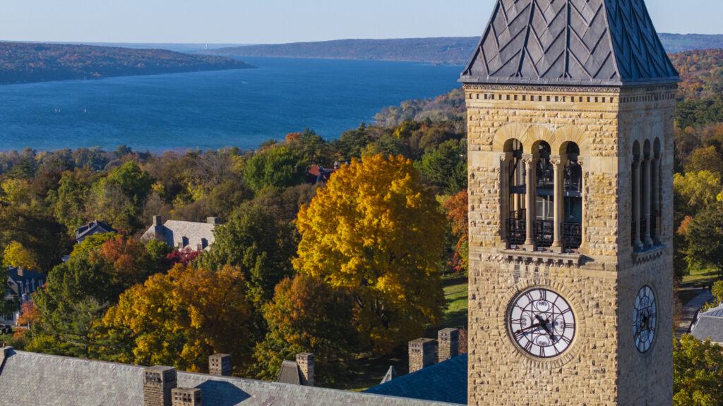 The top of McGraw Tower with fall foliage and Cayuga Lake in the background.