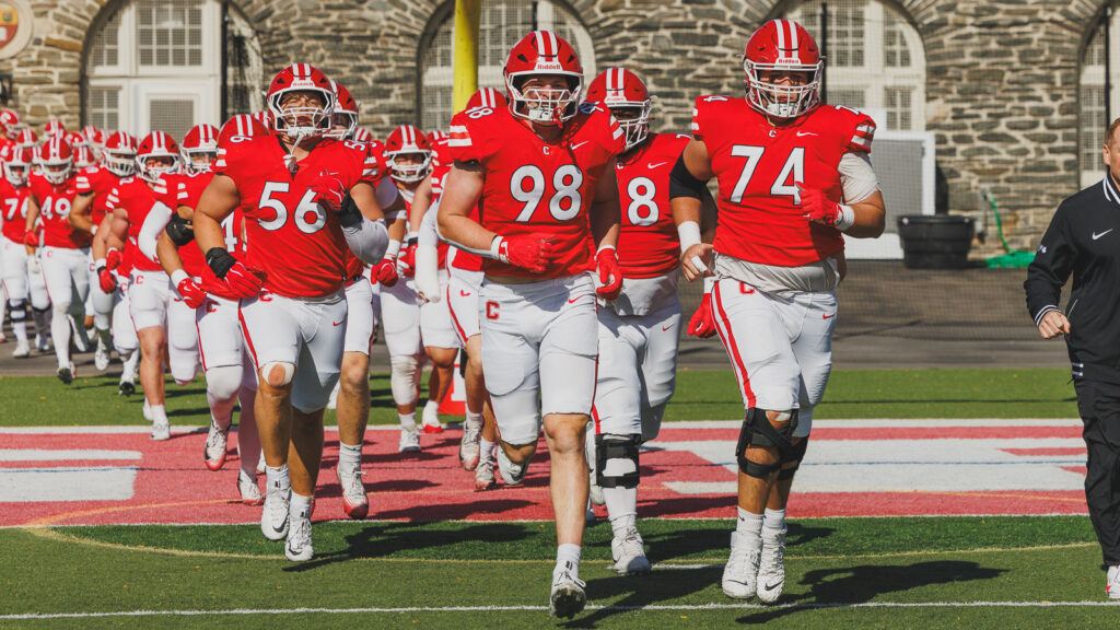 Cornell football players run out onto the field at the start of the game.