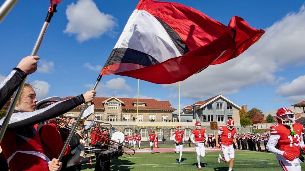 Members of the marching band wave flags as the football team run out at the start of the game.