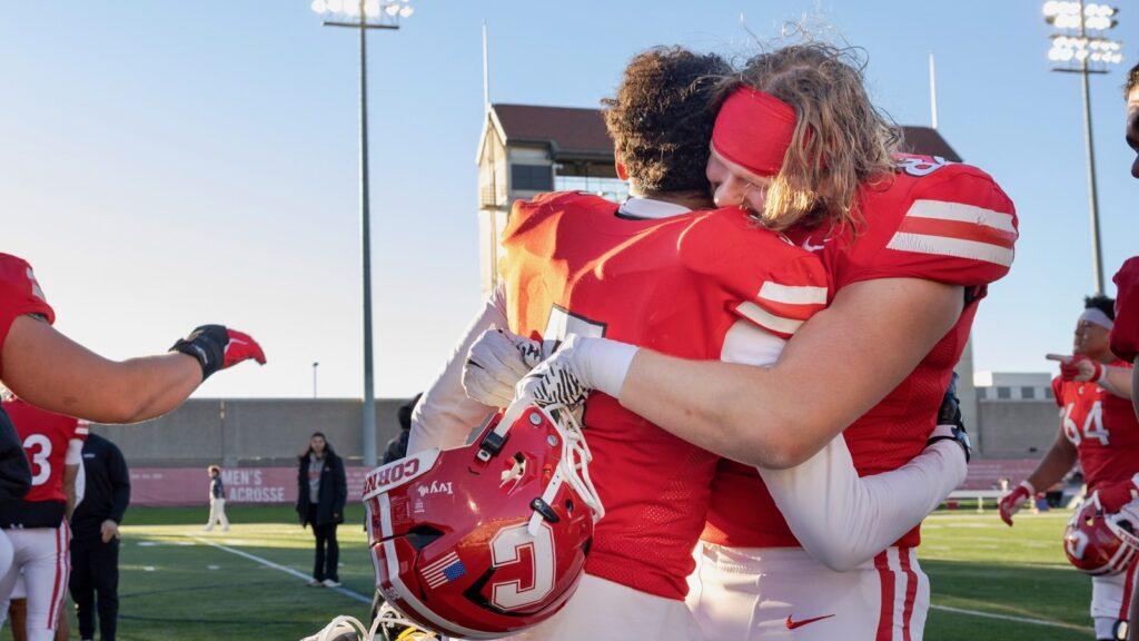 Two Cornell football players hug on the field.