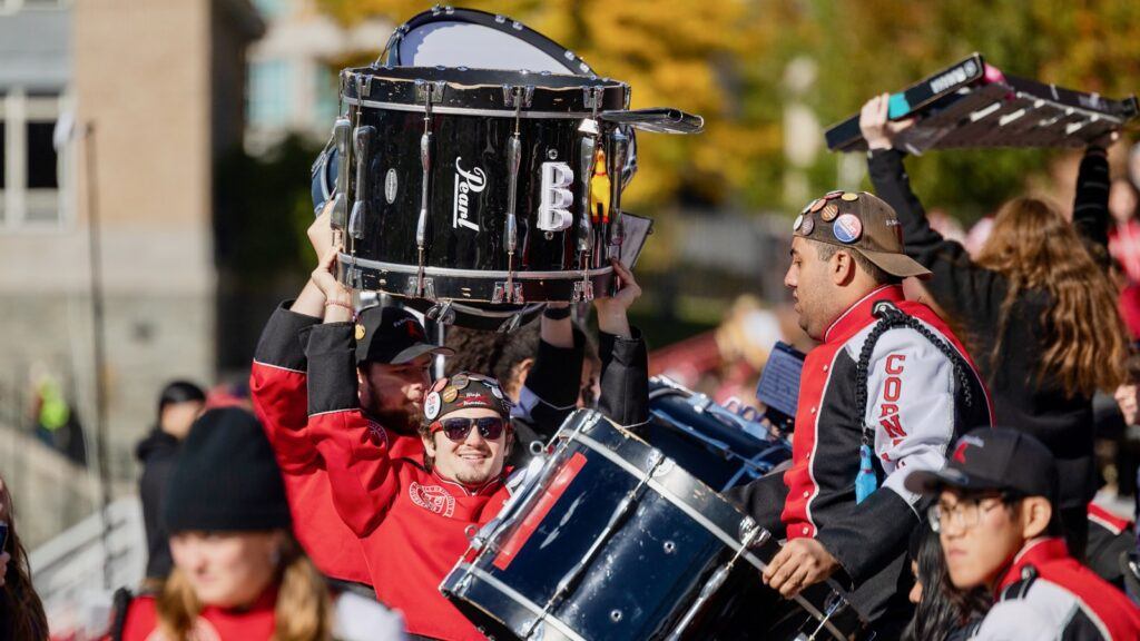Cornell marching band moves their percussion instruments by carrying them over their heads.