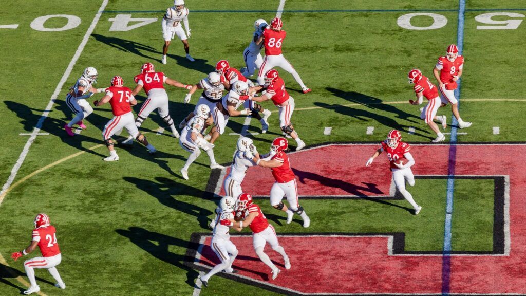 Cornell football players block Lehigh as a Cornell player runs the ball down the field.