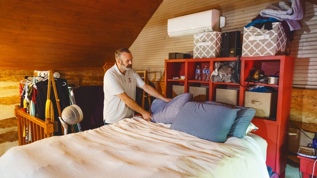 Michael Oak makes the bed in the cabin's half-loft bedroom