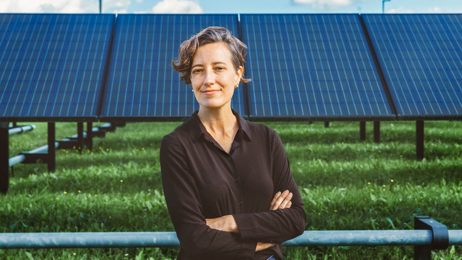 Holly Jean Buck stands in front of a solar farm