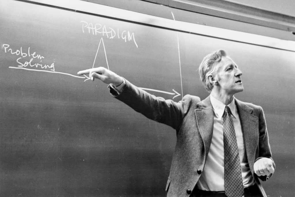 Frank H.T. Rhodes gestures in front of a classroom chalkboard early in his presidency