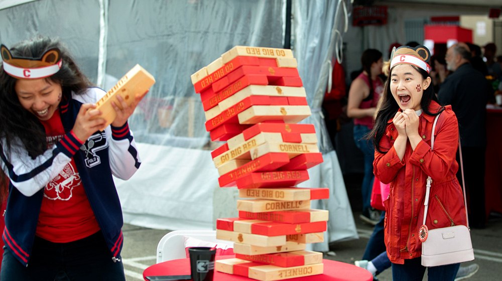 Visitors playing a giant Jenga game at the tailgate tent for alumni and parents.