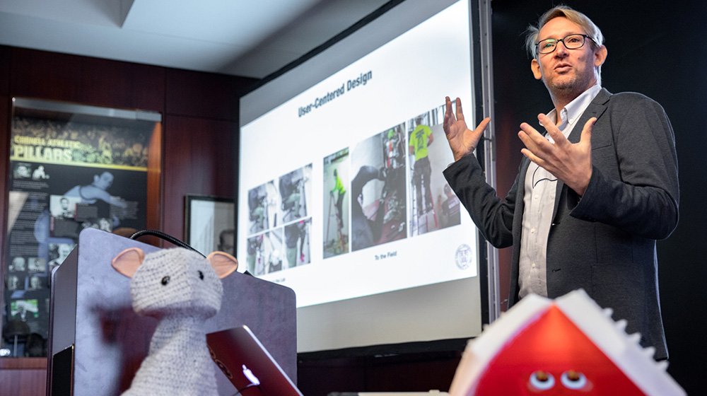 Guy Hoffman, the Mills Family Faculty Fellow and assistant professor of mechanical and aerospace engineering, gives a Return to the Classroom lecture on robots and emotions, aided by two robot friends (foreground.)