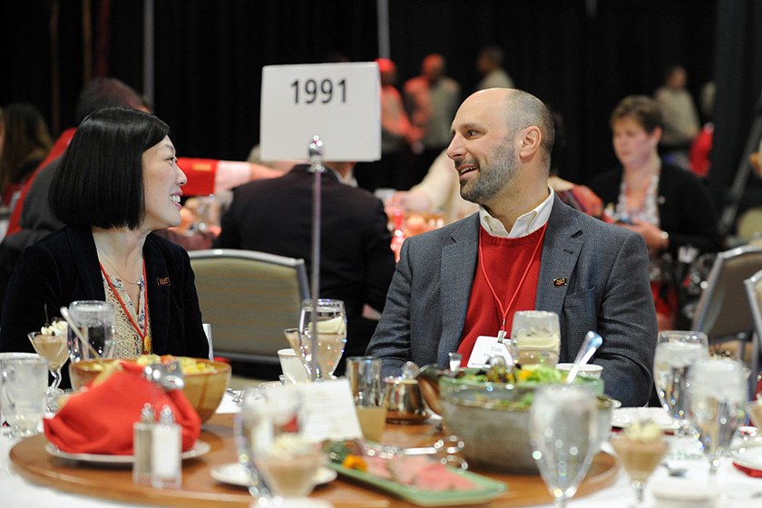 Two alumni, Class of 1991, chat before a meal.