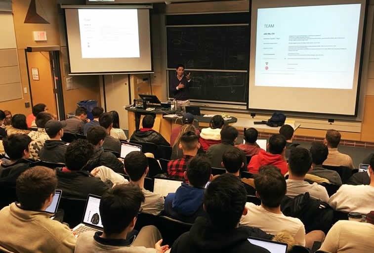 John Wu speaking at the front of a classroom