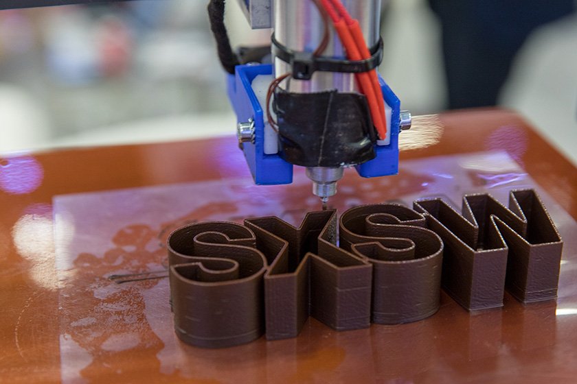 A 3-D printer creating block letters: "SXSW"