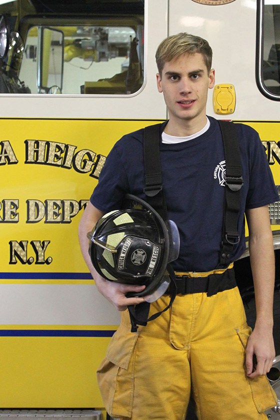 Frank Langrais holding his helmet in front of a Cayuga Heights Fire Department truck.