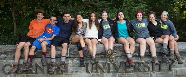 Cornell students linking arms on stone wall
