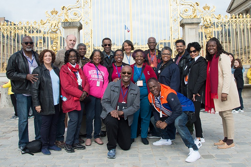 A tour group in front of the golden gates of Versailles.