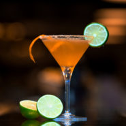 orange cocktail topped with lime slice