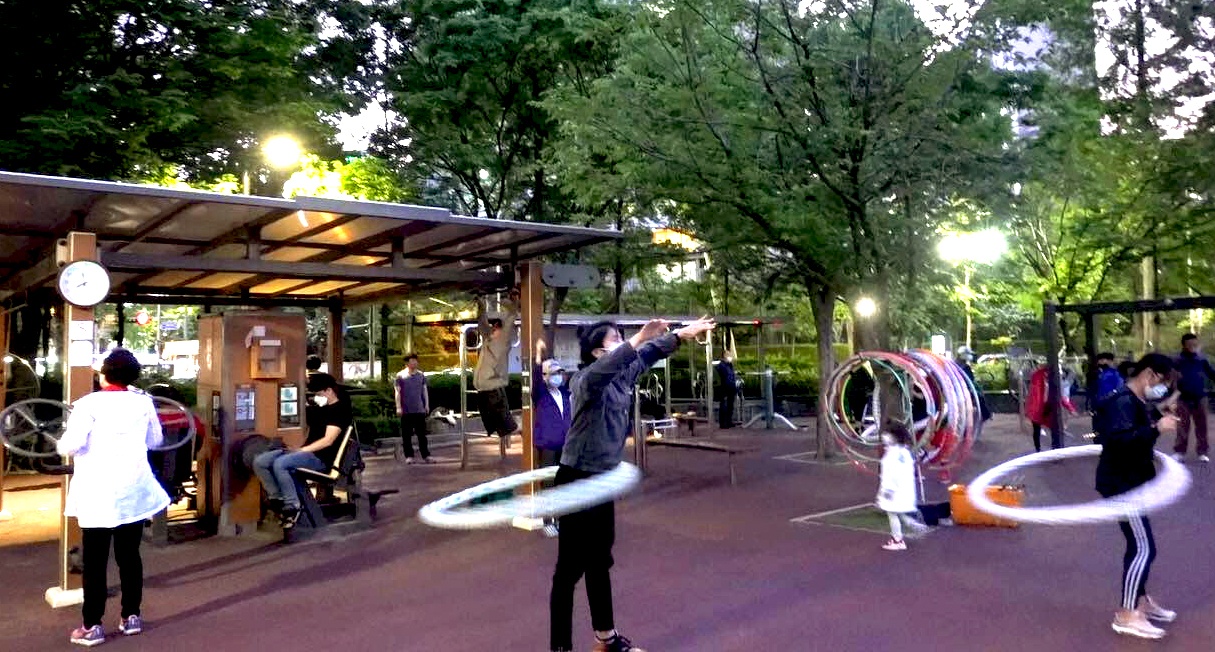 Eric hula-hooping in a public park in Seoul, making sure to wipe down the hoop before and keep two meters away from others.