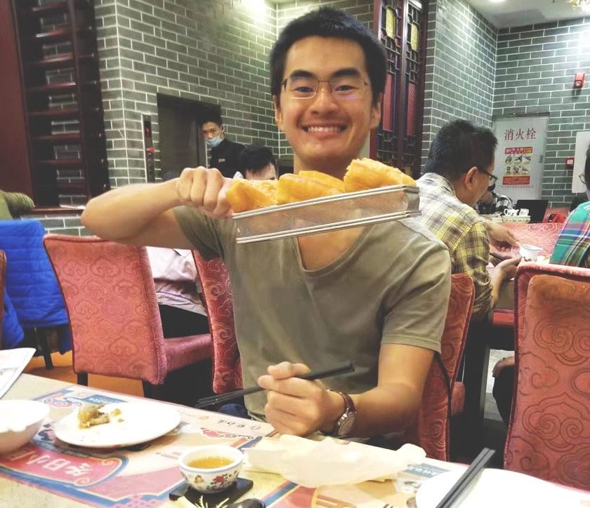 Sebastian in Guangzhou, China, eating a dish called youtiao, which is basically long strips of dough deep fried.
