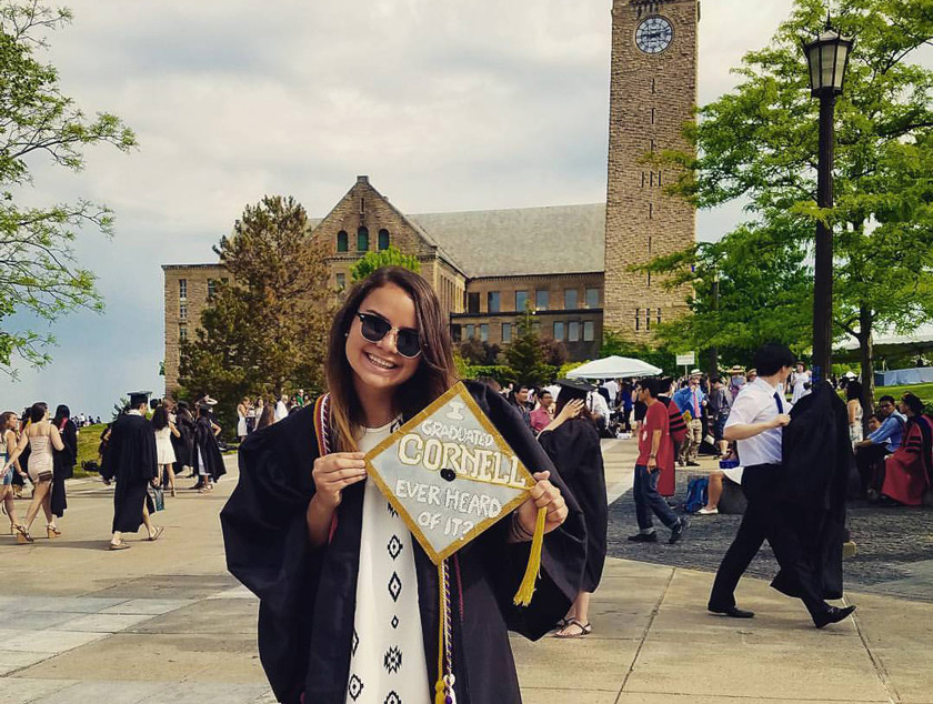 Camila Salazar on graduation day, in front of the clock tower. Her graduation cap says, "I graduated CORNELL, ever heard of it?," a nod to the infamous Andy Bernard reference to Cornell in The Office.