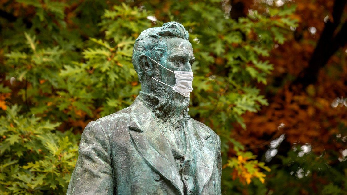 The statue of Ezra Cornell complies with the university's mask mandate. Photo Credit: Jason Koski