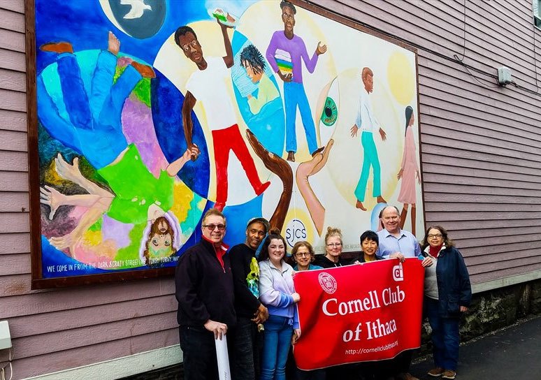 Cornell Club of Ithaca members standing beneath a mural in Ithaca