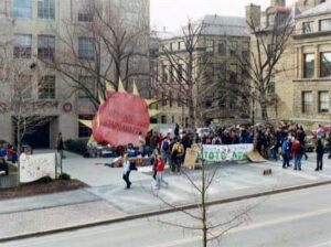 The massive sun reads, “Demand Sustainability.” Kyoto Now! students hung it above ‘Kyoto Village’ in April 2001.