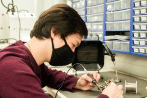 Alan Hsiao ’21 solders a circuit board in lab.